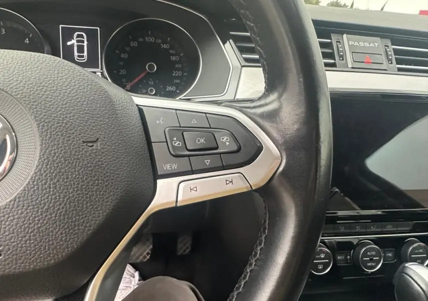 Vue rapprochée du volant cuir multifonctions et du tableau de bord numérique de la Volkswagen Passat gris foncé Business 2021.