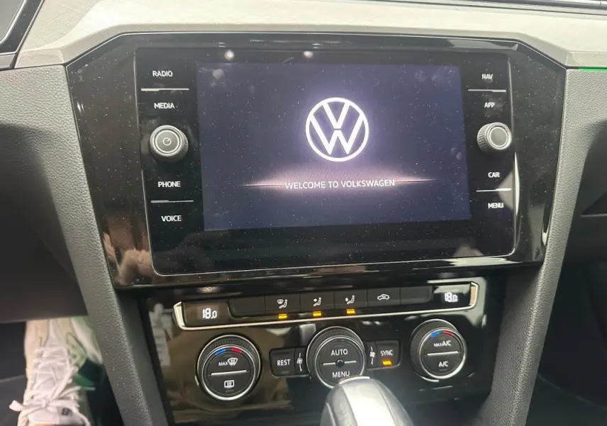 Vue rapprochée du tableau de bord de la Volkswagen Passat Business gris foncé, mettant en valeur l'écran tactile et les commandes de climatisation.