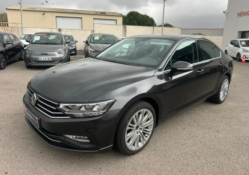 Volkswagen Passat Business gris foncé vue 3/4 avant droit avec jantes alliage 17 pouces sur parking.