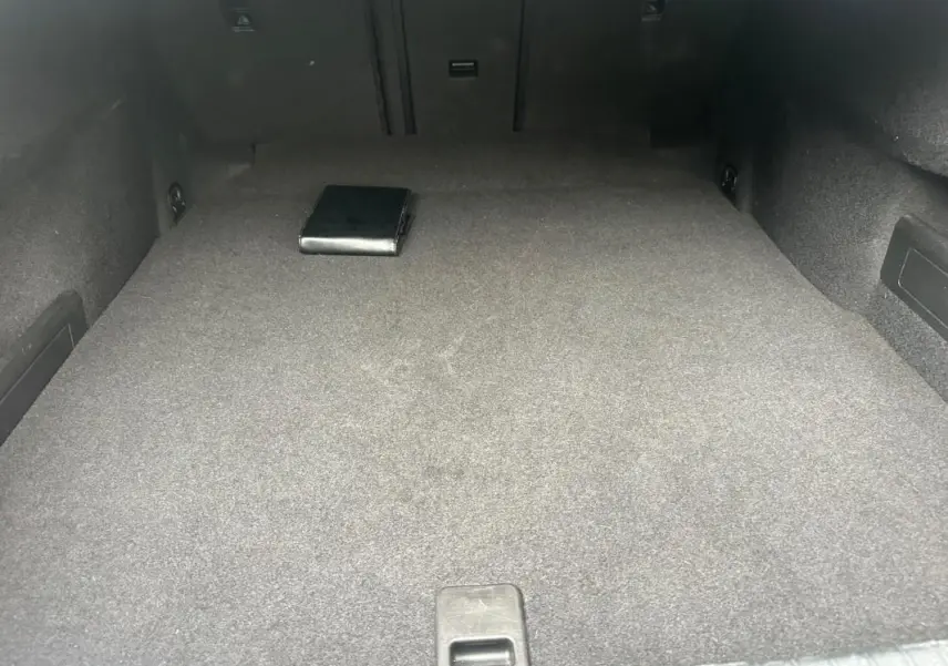 Coffre spacieux gris foncé de la Volkswagen Passat Business 2021, avec un manuel posé à l'arrière.