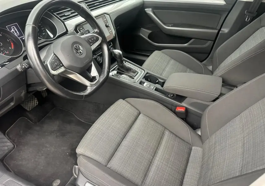 Intérieur gris clair de la Volkswagen Passat Business 2021, vue côté conducteur sur volant cuir et console centrale avec boîte auto.