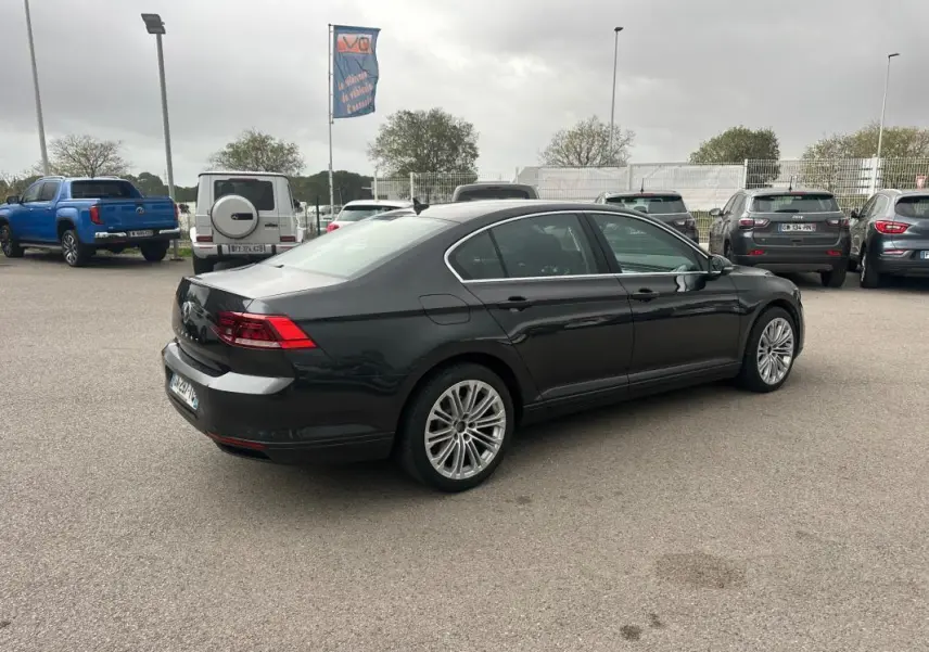 Volkswagen Passat Business gris foncé vue 3/4 arrière droit sur parking avec jantes alliage 17 pouces.