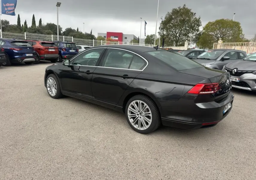 Volkswagen Passat gris foncé vue 3/4 arrière droit, jantes alliage 17 pouces, stationnée en extérieur sur parking.