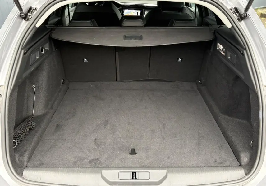 Coffre ouvert vu de l'arrière d'une Peugeot 308 SW gris Artense, avec cache-bagages et intérieur noir.