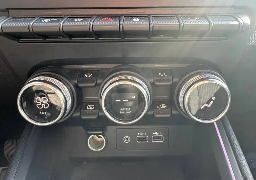 Vue rapprochée des commandes de climatisation et des ports USB de la Renault Clio Rouge Flamme 2025.