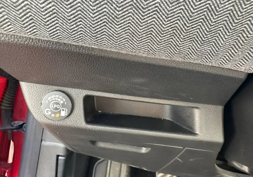 Détail intérieur montrant le témoin de carburant GPL sous le siège avant d’une Renault Clio Rouge Flamme.