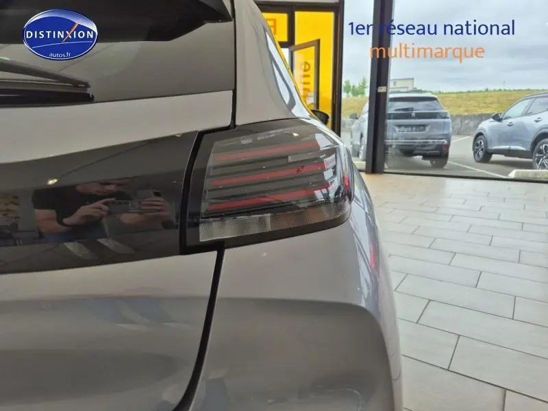 Gros plan sur le feu arrière gauche d'une Peugeot 208 1.2 100ch S&S Allure gris Artense dans un showroom lumineux.