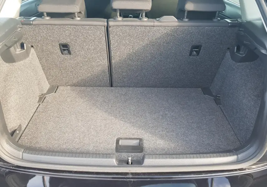 Coffre ouvert d'une Volkswagen Polo noire de 2018, vue arrière montrant l'espace de chargement vide et tapis gris.