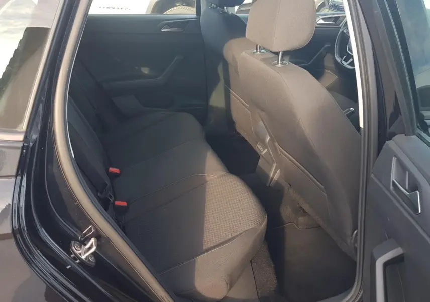 Vue intérieure côté arrière gauche d'une Volkswagen Polo noire 2018, montrant la banquette arrière et les sièges avant en tissu noir.