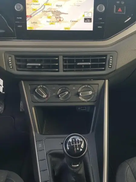 Vue intérieure centrée sur la console centrale d'une Volkswagen Polo noire 2018 avec levier de vitesses manuel et écran tactile GPS.