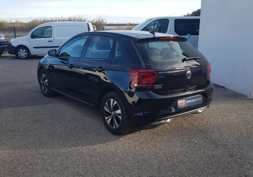 Volkswagen Polo noire vue 3/4 arrière côté gauche, avec jantes alliage et feux arrière distinctifs.
