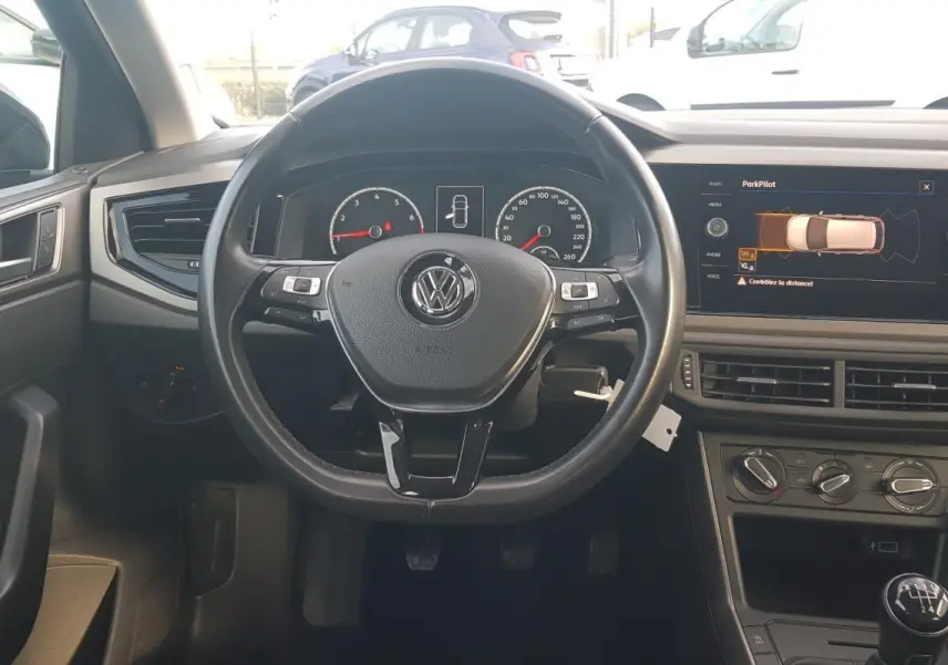 Vue intérieure frontale du volant cuir multifonctions et tableau de bord numérique de la Volkswagen Polo noire 2018.