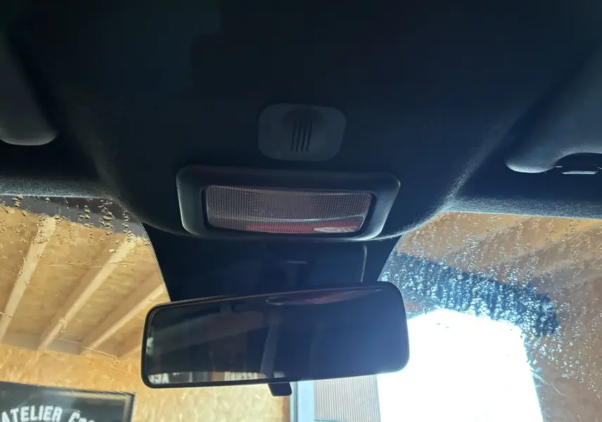 Vue intérieure centrée sur le rétroviseur intérieur et le plafonnier d'une Fiat 500 blanche, avec fenêtre partiellement embuée.