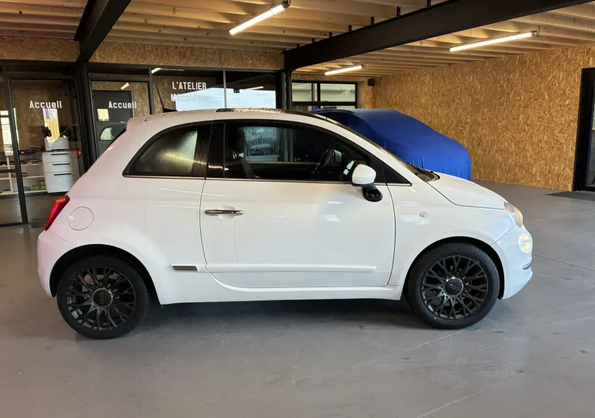 Profil droit d'une FIAT 500 blanche de 2021, avec jantes noires et intérieur visible à travers les vitres teintées.
