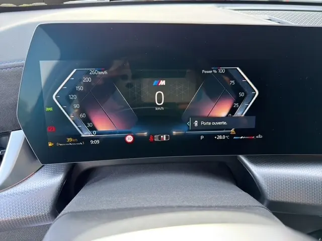Vue du tableau de bord numérique du BMW X2 noir 2025, affichant la vitesse et une alerte porte ouverte.