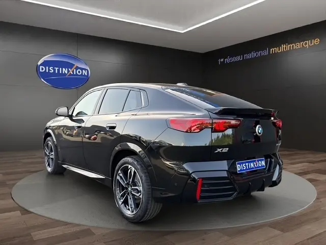 BMW X2 sDrive20d M Sport noir vue 3/4 arrière droit, avec jantes alliage et spoiler de toit distinctifs.