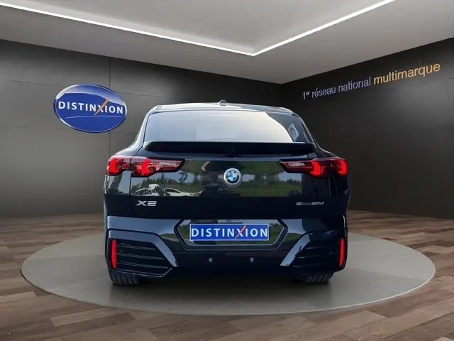 Vue arrière d'un BMW X2 sDrive20d M Sport DKG7 noir, avec feux LED et logo Distinxion visible en arrière-plan.