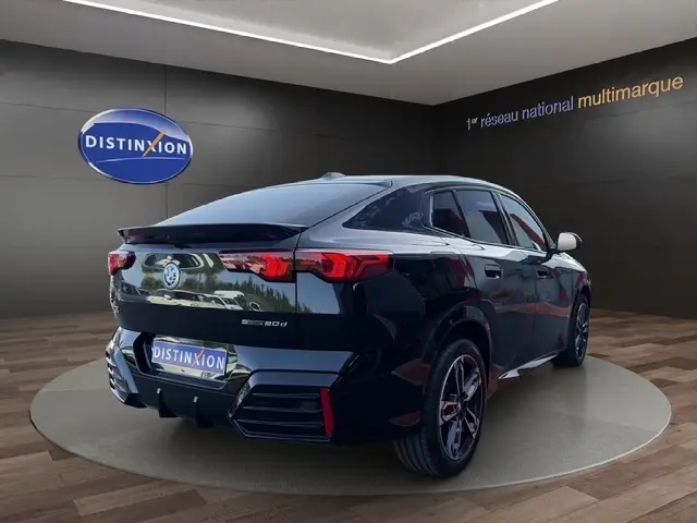 Vue 3/4 arrière droite d’un BMW X2 sDrive20d M Sport noir brillant, avec feux arrière LED et jantes sport.