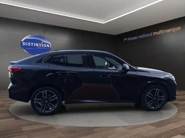 BMW X2 sDrive20d M Sport noir en profil droit, avec jantes sport et toit incliné dans un showroom.