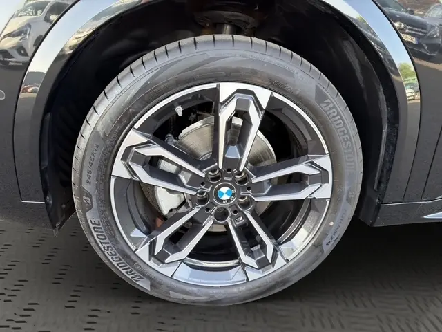 Gros plan sur la roue avant droite du BMW X2 noir, mettant en valeur la jante alliage au design moderne.