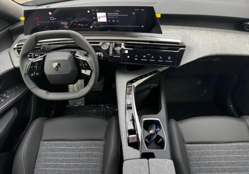 Intérieur Peugeot 5008 2025 vu de dessus, volant compact, tableau de bord numérique et sellerie tissu gris et noir.
