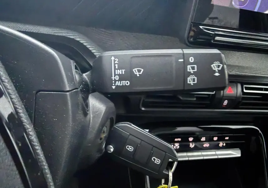 Gros plan sur la commande d’essuie-glace et la clé de contact dans l’habitacle noir de la Citroën C3 gris 2025.