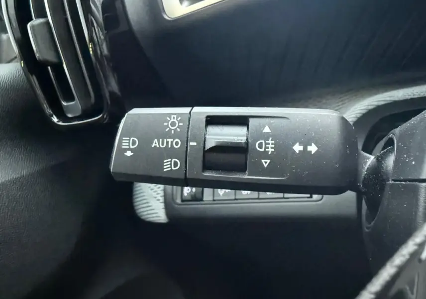 Gros plan sur la commande des feux avec réglage automatique sur le côté gauche du tableau de bord gris du Citroën C3 2025.