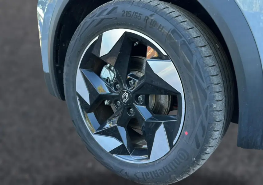 Gros plan sur la roue avant droite du Renault Captur gris rafale, mettant en valeur la jante alu au design étoilé noir et argent.