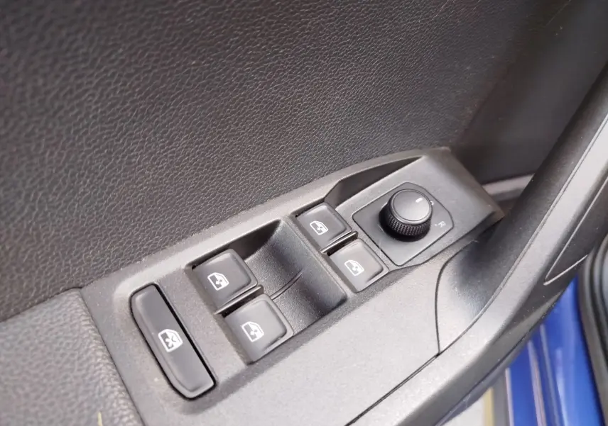 Gros plan sur les commandes de lève-vitres et réglage des rétroviseurs côté conducteur d'une SEAT Arona bleu électrique.