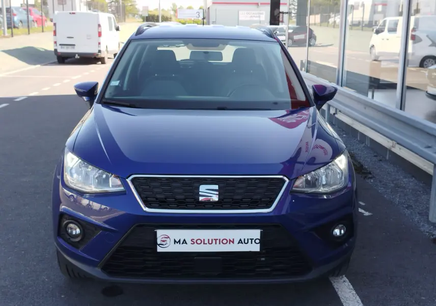 Vue frontale d'un SEAT Arona bleu électrique 2019 avec phares allumés et calandre noire hexagonale.