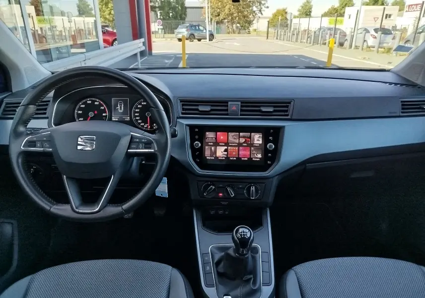 Vue intérieure du tableau de bord et volant d'une SEAT Arona 2019, avec écran tactile et levier de vitesse manuel.