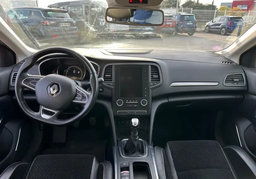 Intérieur noir de la Renault Mégane Break IV TCe 130, vue frontale du tableau de bord avec volant cuir et boîte manuelle.