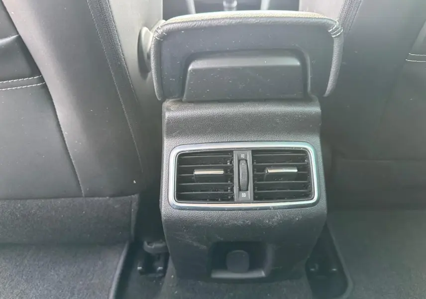 Bouche d'aération arrière noire encadrée de chrome entre les sièges avant d'une Renault Mégane Break gris clair.