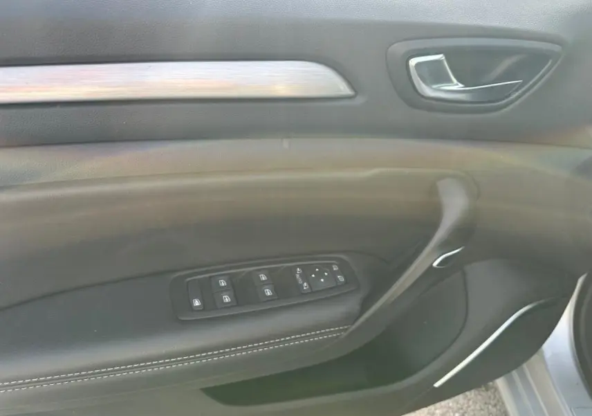 Gros plan sur la porte côté conducteur de la Renault Mégane Break gris clair, avec commandes électriques et finition cuir.