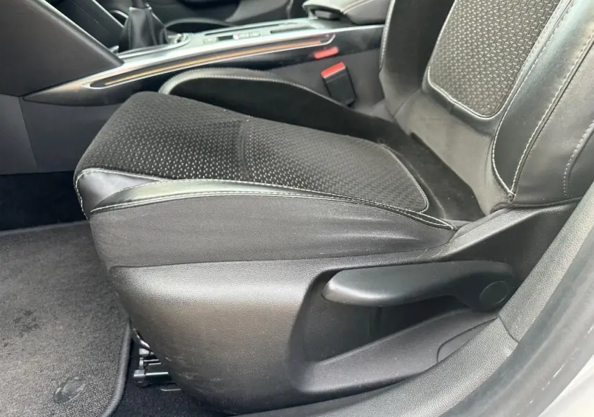 Gros plan sur le siège conducteur noir en tissu et cuir du Renault Mégane Break IV gris clair, intérieur soigné.