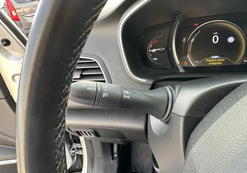 Vue rapprochée du tableau de bord et du volant cuir d'une Renault Mégane Break gris clair, affichage tête haute actif.