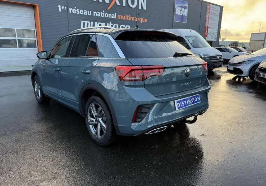 Volkswagen T-Roc bleu pétrole métallisé vu en 3/4 arrière droit avec attelage amovible et jantes Valencia gris galvanisé.