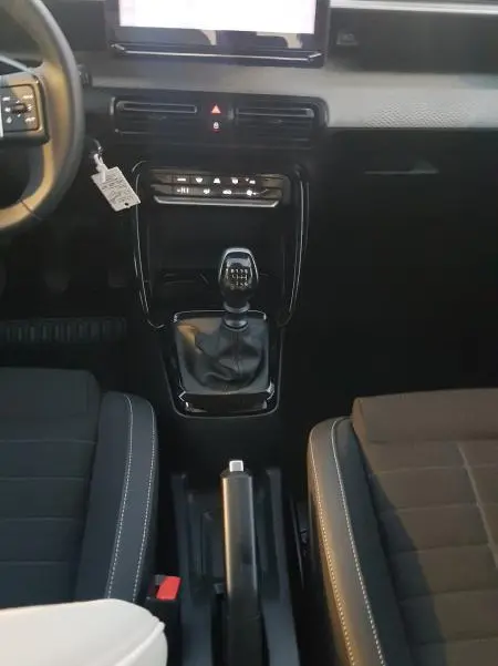 Vue intérieure centrée sur la console centrale et levier de vitesses manuelle d'une Citroën C3 noire 2025.