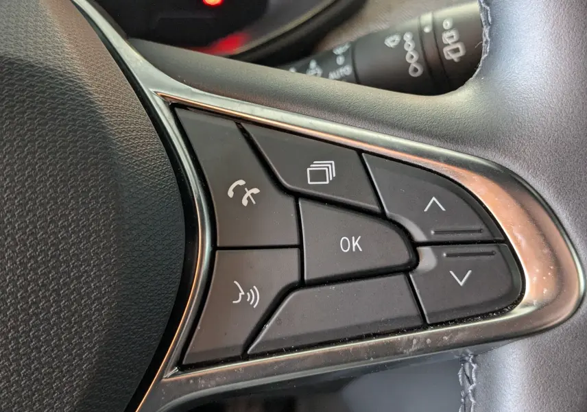 Gros plan sur les commandes multifonctions noires du volant côté droit d'une Renault Clio gris schiste métal 2025.