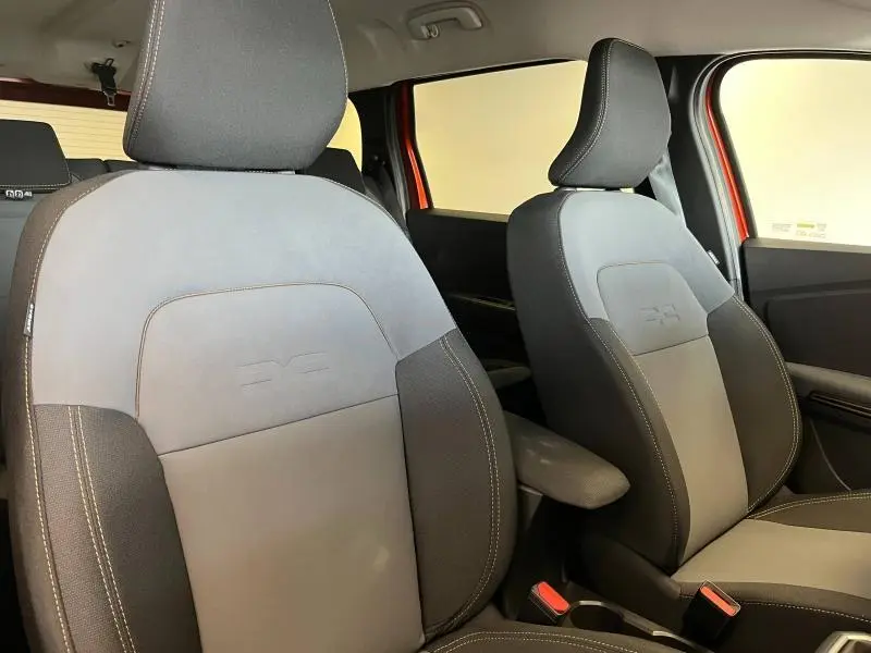 Vue rapprochée des sièges avant gris et noir de la Dacia Jogger 2024 avec détails orange visibles sur la portière.