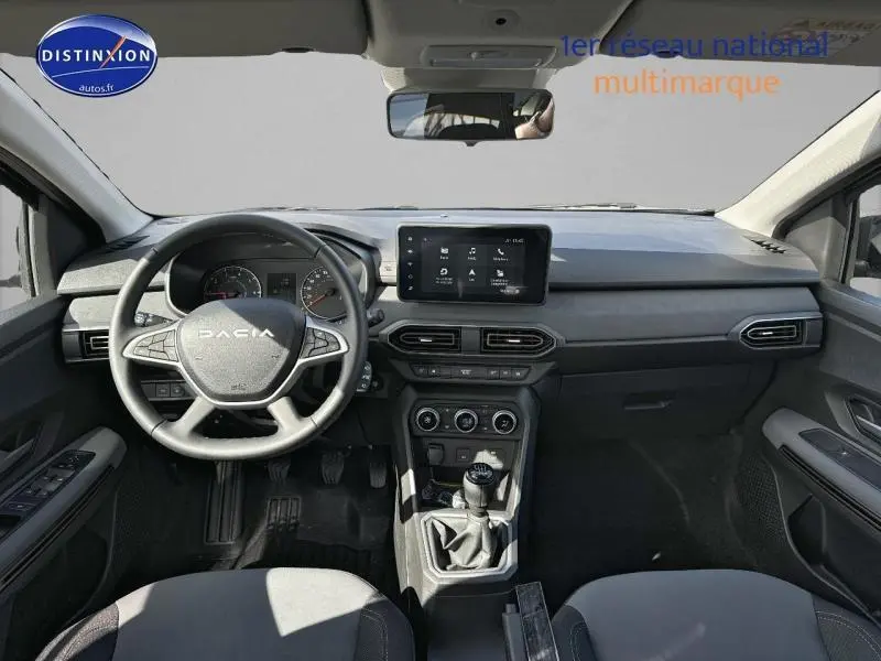 Vue intérieure avant du tableau de bord et volant noir de la Dacia Jogger 2024 avec écran tactile et boîte manuelle.