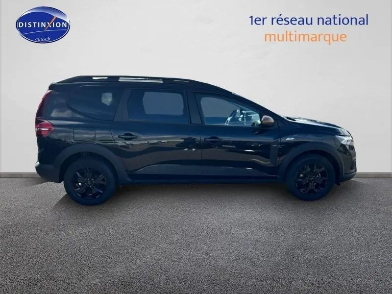 Vue latérale droite du Dacia Jogger 2024 noir nacré métallisé avec barres de toit et jantes noires.