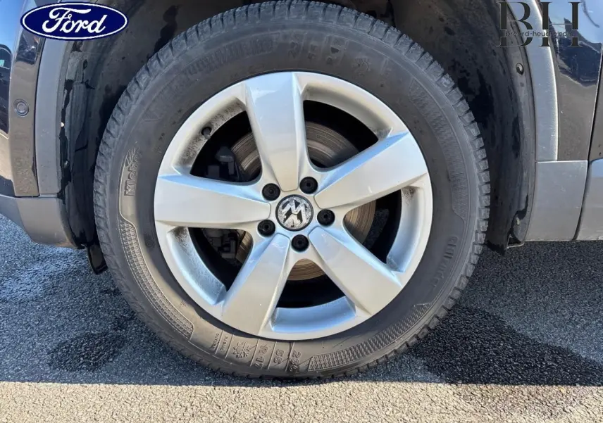 Gros plan sur la roue avant droite d'un Volkswagen Tiguan beige, mettant en valeur la jante alu à cinq branches.