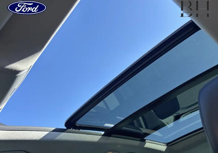 Toit ouvrant panoramique ouvert sur ciel bleu, vue intérieure du Volkswagen Tiguan beige 2010