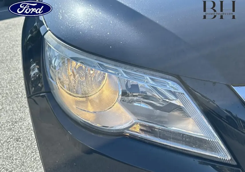 Gros plan sur le phare avant droit d’un Volkswagen Tiguan beige, mettant en valeur les détails du bloc optique et la carrosserie.