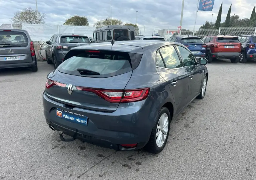 Renault Mégane IV gris foncé vue 3/4 arrière droit sur parking, avec feux arrière LED et attelage visible
