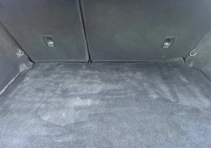 Coffre vide de la Renault Mégane IV Berline gris foncé vu de l'intérieur arrière, avec tapis de sol propre et fixations ISOFIX visibles.