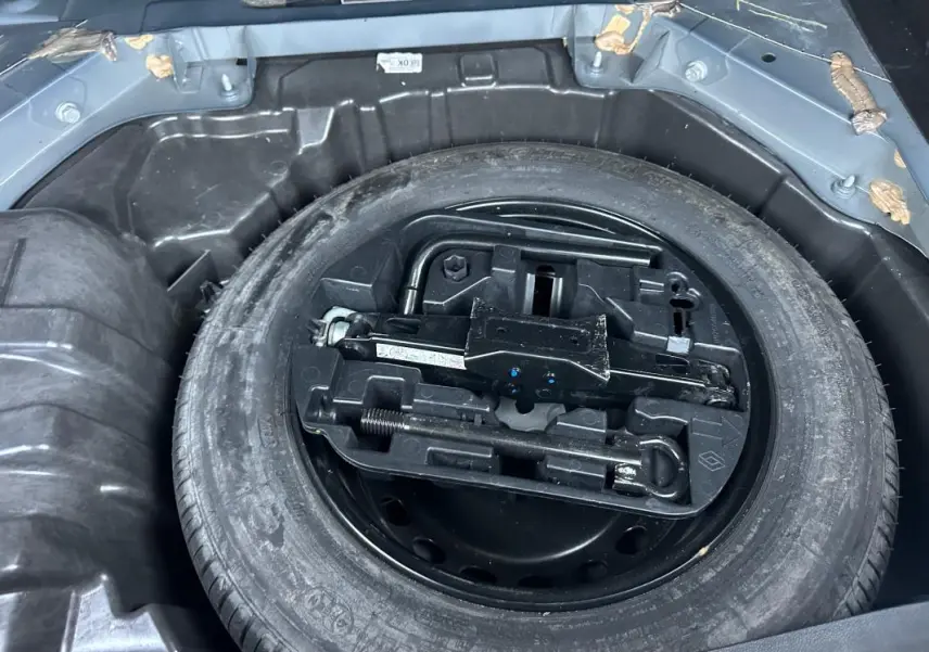 Roue de secours et kit de dépannage dans le coffre d'une Renault Mégane IV gris foncé, vue en plongée.