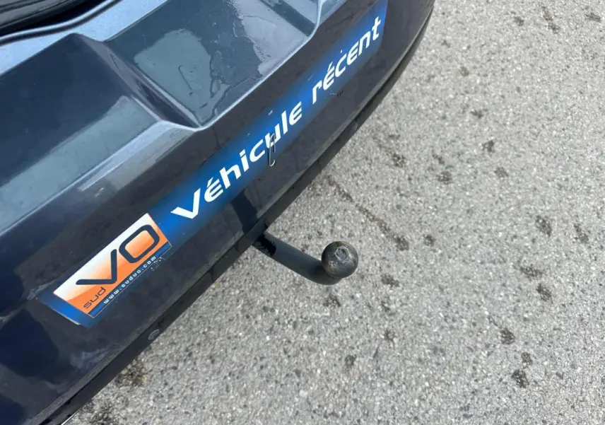 Gros plan sur l'attelage arrière d'une Renault Mégane IV gris foncé avec autocollant V.O Véhicule récent.