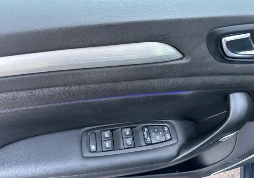 Panneau de porte côté gauche en cuir noir avec commandes électriques des vitres et rétroviseurs d'une Renault Mégane IV gris foncé.